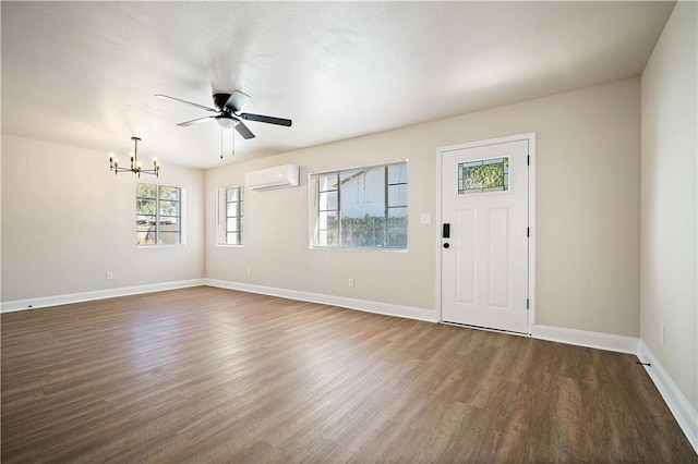 entryway featuring ceiling fan with notable chandelier, baseboards, dark wood-type flooring, and a wall unit AC