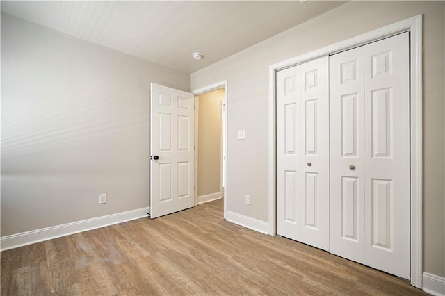 unfurnished bedroom with a closet, baseboards, and wood finished floors