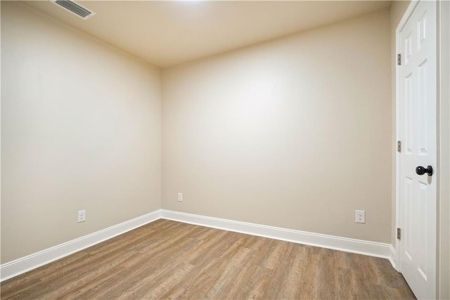 empty room featuring visible vents, baseboards, and wood finished floors