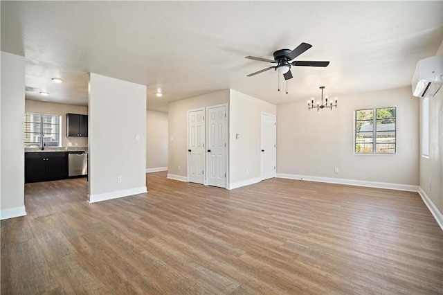 unfurnished living room with light wood finished floors, ceiling fan with notable chandelier, a wall mounted AC, and baseboards