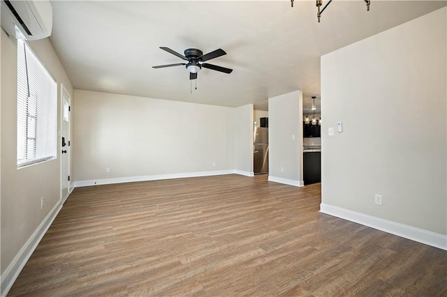 unfurnished living room featuring baseboards, wood finished floors, a ceiling fan, and a wall mounted AC