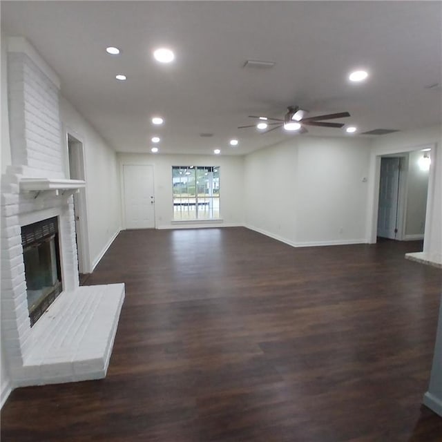 unfurnished living room with dark hardwood / wood-style flooring and a brick fireplace