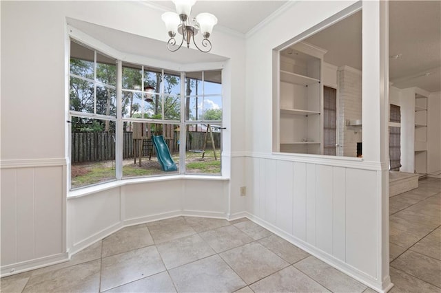 unfurnished dining area with tile patterned flooring, ornamental molding, an inviting chandelier, and built in shelves