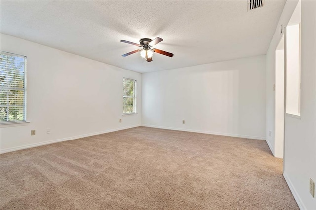 carpeted spare room featuring ceiling fan and a textured ceiling