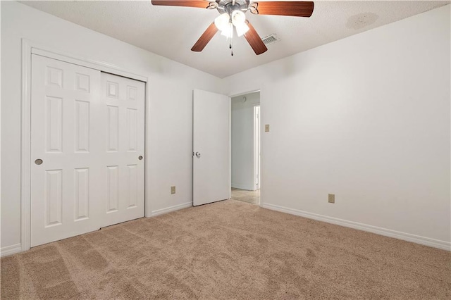 unfurnished bedroom featuring light carpet, a closet, and ceiling fan