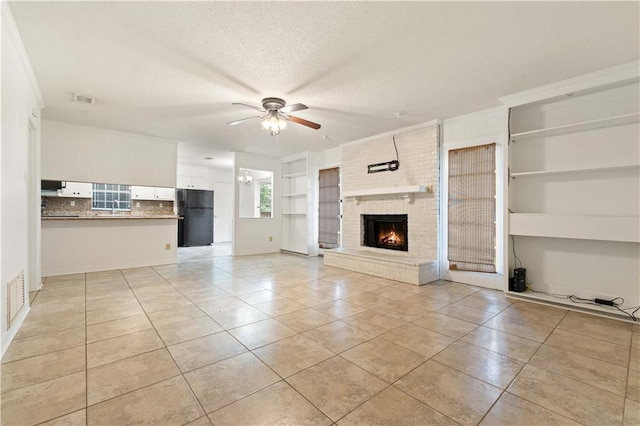 unfurnished living room with a brick fireplace, light tile patterned floors, a textured ceiling, built in features, and ceiling fan