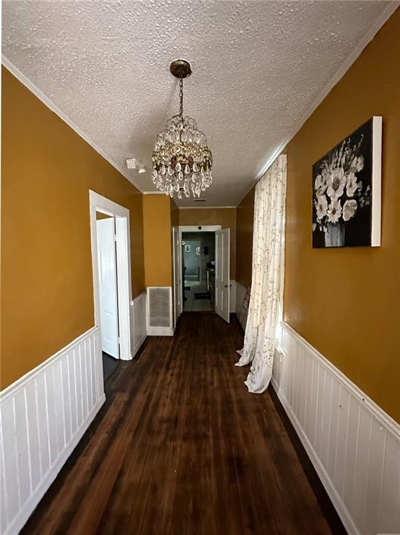 hallway featuring dark hardwood / wood-style flooring, a textured ceiling, and a chandelier