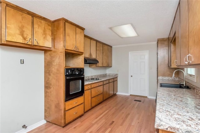 kitchen featuring black oven, light hardwood / wood-style floors, gas stovetop, sink, and a textured ceiling