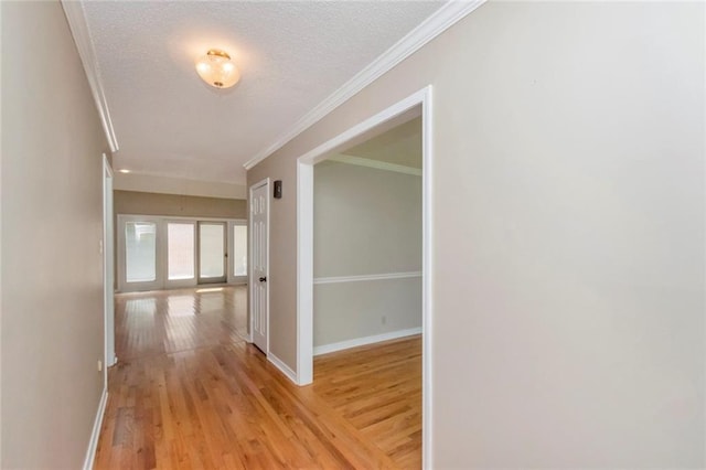 corridor featuring light hardwood / wood-style floors, a textured ceiling, and crown molding