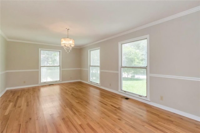 empty room featuring a notable chandelier, light hardwood / wood-style flooring, and crown molding