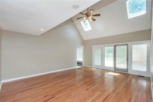 unfurnished room featuring high vaulted ceiling, light wood-type flooring, a skylight, and ceiling fan