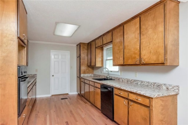 kitchen featuring crown molding, black appliances, light wood-type flooring, sink, and a textured ceiling