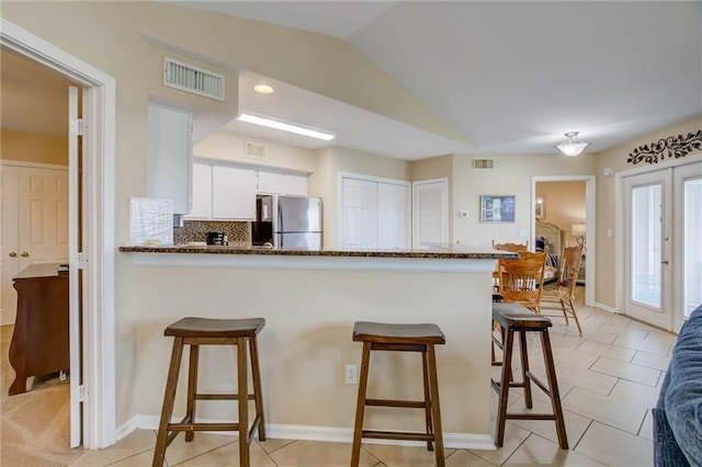 6194 State Highway 59 Unit D-8, Gulf Shores, AL 36542 - kitchen featuring freestanding refrigerator, a peninsula, white cabinets, a kitchen breakfast bar, and dark stone countertops