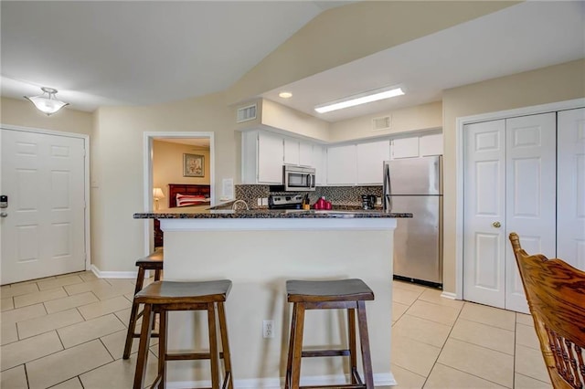6194 State Highway 59 Unit D-8, Gulf Shores, AL 36542 - kitchen with appliances with stainless steel finishes, light tile patterned floors, a kitchen bar, backsplash, and vaulted ceiling