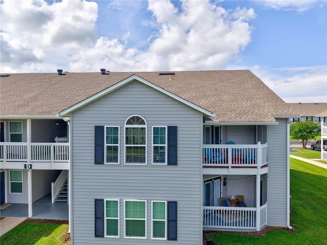 6194 State Highway 59 Unit D-8, Gulf Shores, AL 36542 - rear view of property featuring a balcony, a yard, a patio, a shingled roof, and stairs