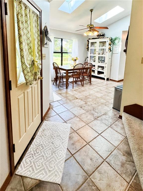 interior space featuring ceiling fan and lofted ceiling with skylight