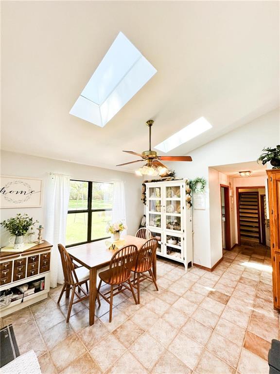 dining area featuring ceiling fan and lofted ceiling with skylight