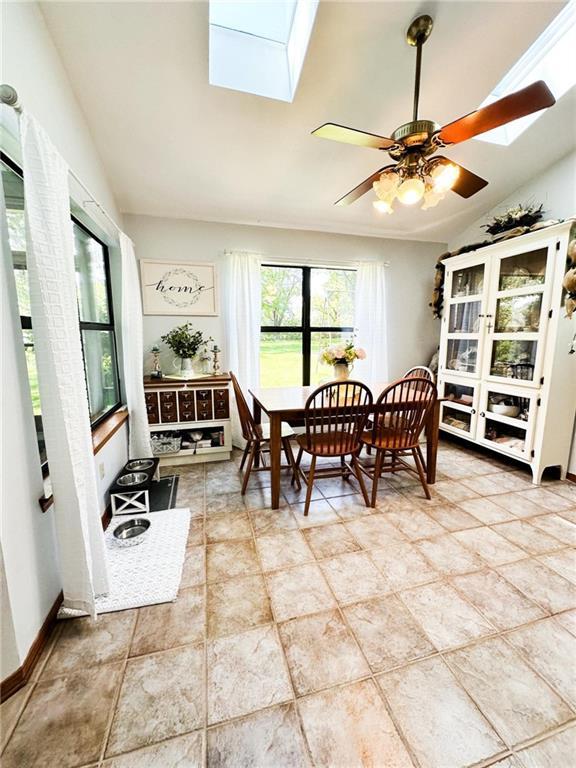 dining room featuring ceiling fan and vaulted ceiling with skylight