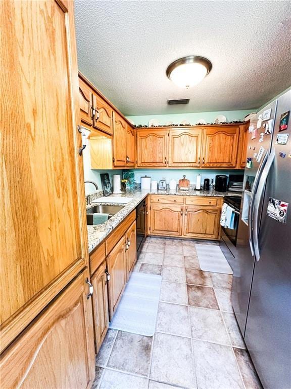 kitchen featuring black dishwasher, sink, stainless steel fridge with ice dispenser, and a textured ceiling