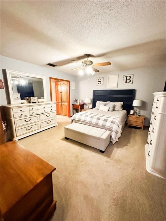 carpeted bedroom featuring ceiling fan and a textured ceiling