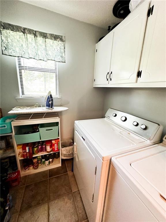 washroom with cabinets, dark tile patterned flooring, and washer and clothes dryer