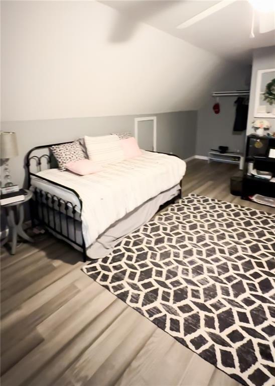 bedroom with ceiling fan, hardwood / wood-style flooring, and lofted ceiling