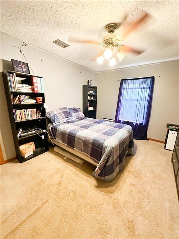 carpeted bedroom with ceiling fan and a textured ceiling