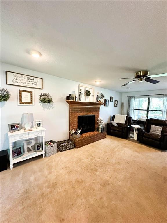 living room featuring ceiling fan, carpet flooring, and a fireplace