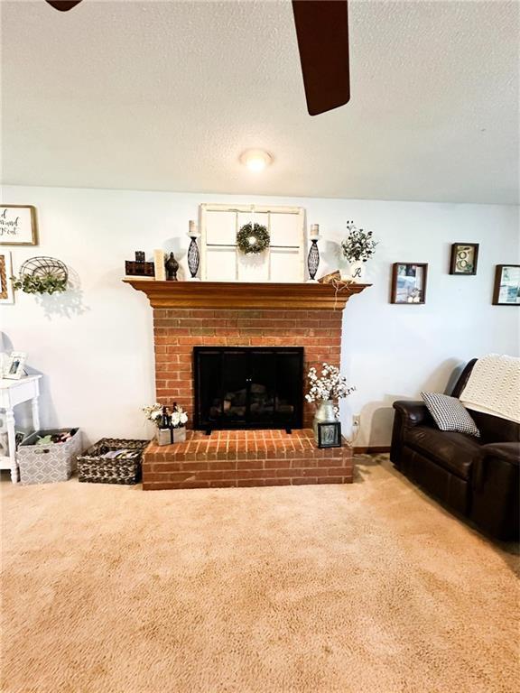 carpeted living room with a textured ceiling, ceiling fan, and a fireplace