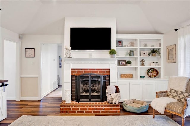 living area featuring baseboards, lofted ceiling, a brick fireplace, and wood finished floors