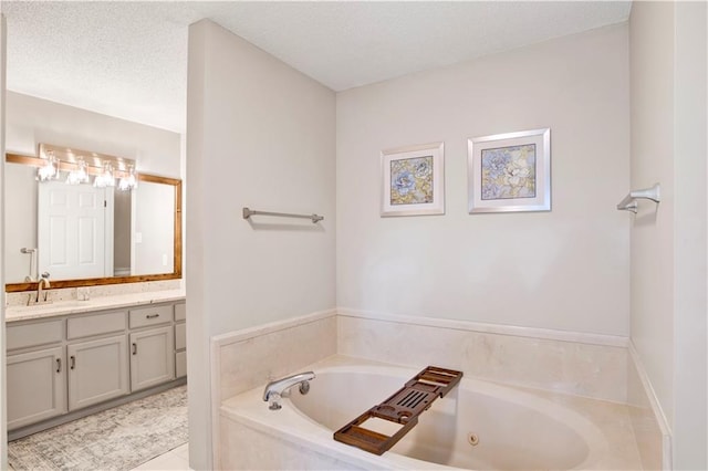 bathroom with a textured ceiling, a tub with jets, and vanity