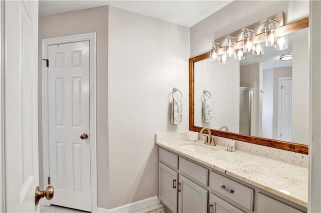 full bath with vanity, a shower stall, baseboards, and a textured ceiling