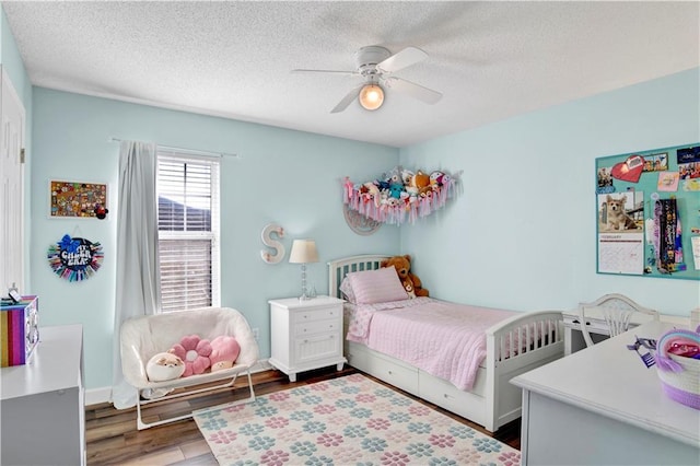 bedroom with a ceiling fan, wood finished floors, baseboards, and a textured ceiling