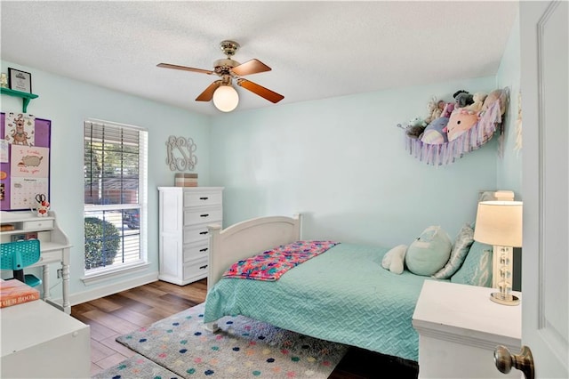 bedroom featuring ceiling fan, wood finished floors, and a textured ceiling