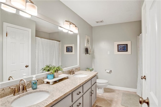 full bath featuring double vanity, toilet, visible vents, and a sink