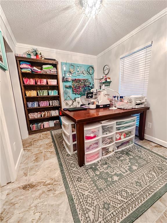 office space featuring a textured ceiling, stone finish floor, baseboards, and ornamental molding