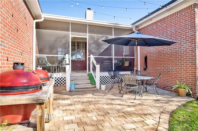 view of patio / terrace featuring grilling area, outdoor dining area, and a sunroom