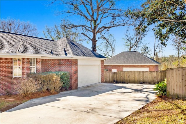 view of property exterior featuring concrete driveway, fence, and brick siding