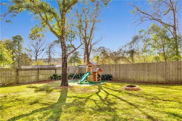 view of yard featuring an outdoor fire pit, a fenced backyard, and a playground