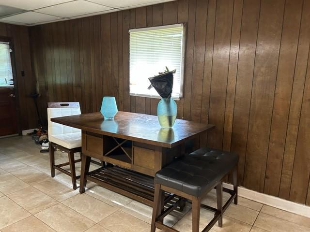 tiled dining room with wood walls and a paneled ceiling