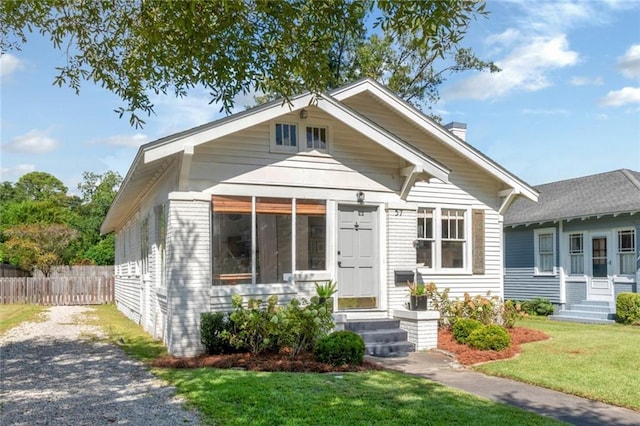 bungalow featuring entry steps, a front lawn, fence, and a chimney