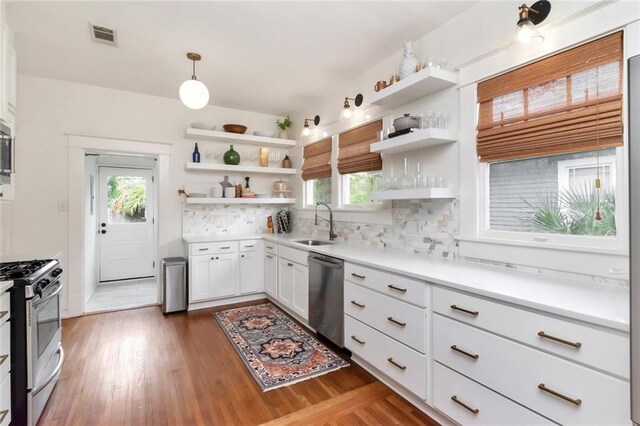 kitchen with open shelves, a sink, appliances with stainless steel finishes, white cabinets, and decorative backsplash