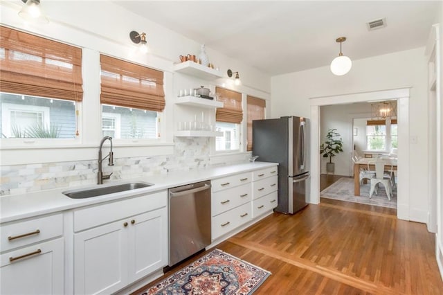 kitchen featuring visible vents, a sink, backsplash, wood finished floors, and appliances with stainless steel finishes