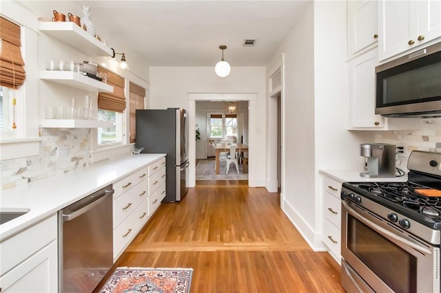 kitchen featuring visible vents, stainless steel appliances, light wood-style floors, white cabinetry, and backsplash