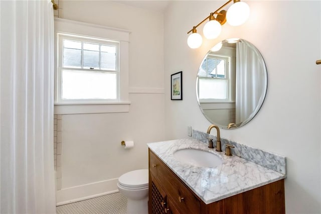 bathroom with vanity, toilet, baseboards, and walk in shower