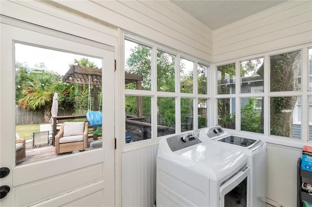 laundry area with laundry area, wooden walls, and washing machine and dryer