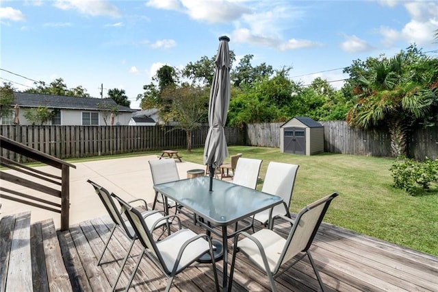 deck featuring an outbuilding, outdoor dining area, a fenced backyard, a yard, and a storage unit