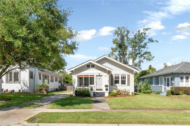 bungalow with a chimney, a front lawn, and entry steps