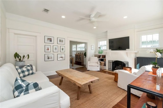 living area featuring visible vents, plenty of natural light, a fireplace, and wood finished floors