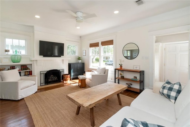 living area featuring visible vents, dark wood-type flooring, recessed lighting, a brick fireplace, and ceiling fan